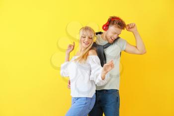 Young couple listening to music on color background�