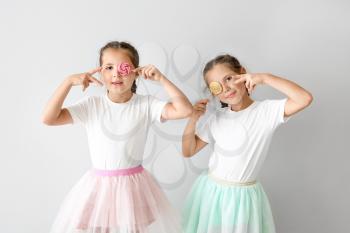 Portrait of funny twin girls with lollipops on light background�
