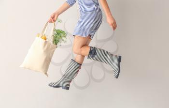Jumping woman with eco bag on light background�