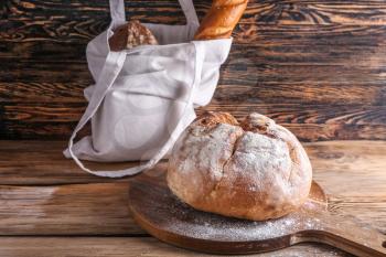 Eco bag with fresh bread on wooden background�