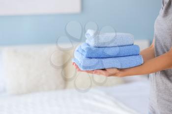 Female housekeeper with clean towels in bedroom�