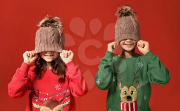 Cute children in Christmas sweaters and hats on color background�