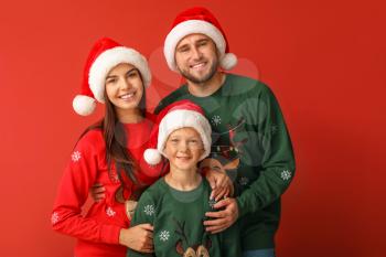 Happy family in Christmas sweaters and Santa hats on color background�