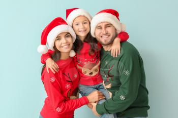 Happy family in Christmas sweaters and Santa hats on color background�