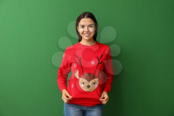 Young woman in Christmas sweater on color background�