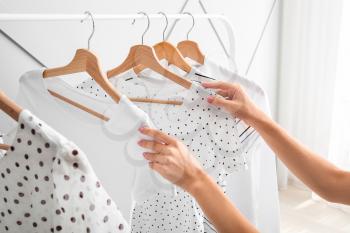 Woman near rack with hanging clothes indoors�