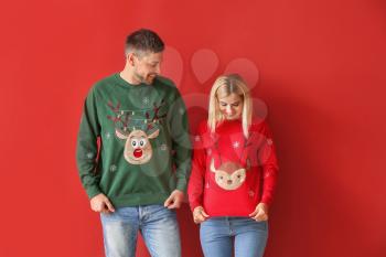 Happy couple in Christmas sweaters on color background�
