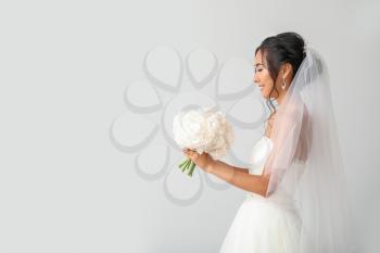 Beautiful young Asian bride on light background�
