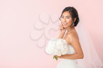 Beautiful young Asian bride on color background�