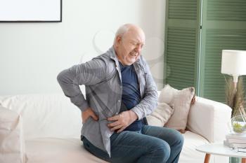Senior man suffering from back pain at home�
