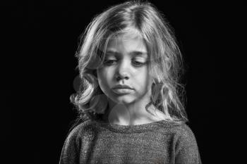 Black and white portrait of sad little girl on dark background�