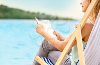 Woman reading book while relaxing on sea beach�