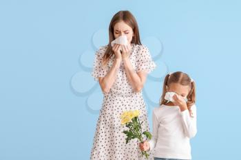 Young woman and little girl suffering from allergy to flowers on light background�