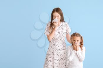 Young woman and little girl suffering from allergy on light background�