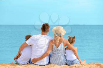 Happy family sitting on sea beach�