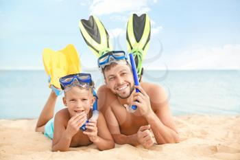 Portrait of happy father and son on sea beach�