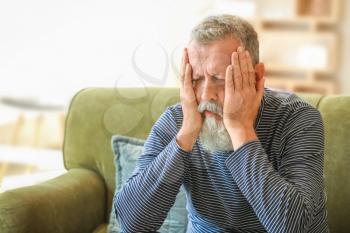 Senior man suffering from headache at home�