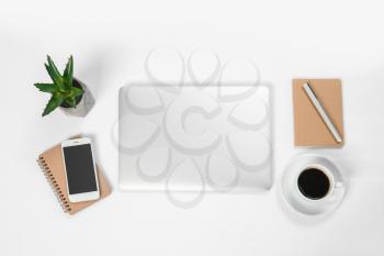 Modern laptop, mobile phone, notebooks and cup of coffee on white background�