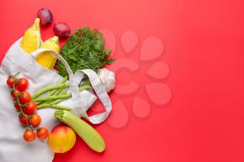 Shopping bag with many healthy vegetables and fruits on color background�