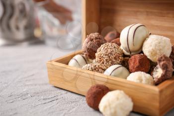 Box with tasty sweet truffles on grey table�