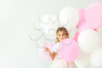 Little girl with balloons on light background�
