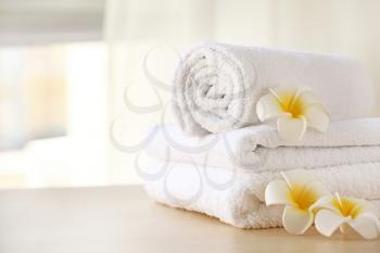 Clean towels with flowers on table in room�