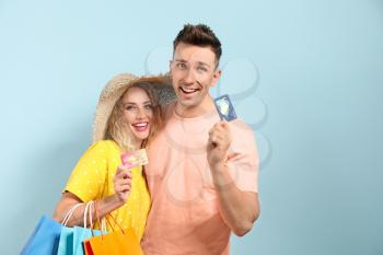 Young couple with credit cards and shopping bags on color background�