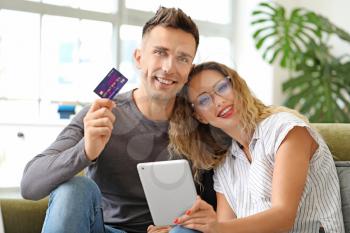 Young couple with credit card and tablet computer at home�