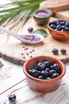 Bowl with fresh acai berries on wooden table�
