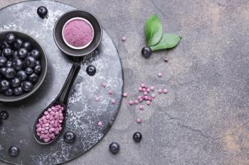 Acai berries with powder and tablets on grey background�
