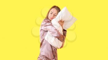 Beautiful young woman with pillow on color background�