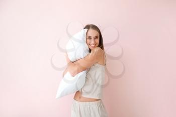 Young woman with pillow on color background�