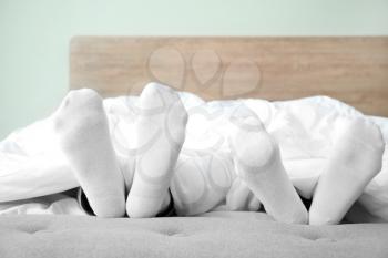 Feet of young couple sleeping in bed�