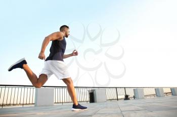 Handsome sporty man running outdoors�