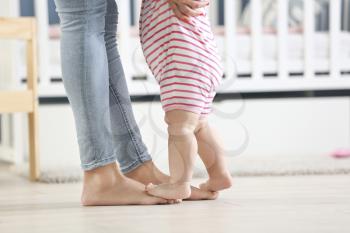 Mother teaching her little baby to walk at home�