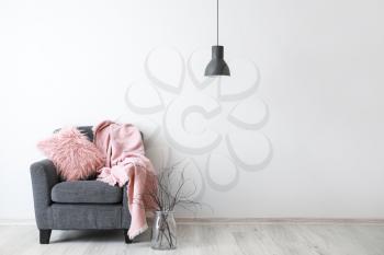 Stylish armchair with plaid near light wall�