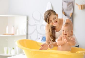 Mother bathing her cute little baby at home�