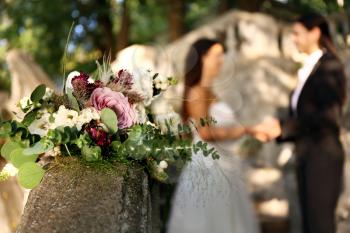 Beautiful wedding bouquet on railing against blurred lesbian couple outdoors outdoors�