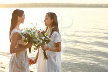 Beautiful lesbian couple on their wedding day near river�