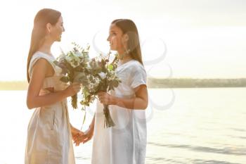 Beautiful lesbian couple on their wedding day near river�