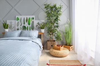 Big comfortable bed and plants in interior of room�