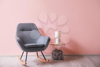 Soft rocking chair with table and lamp near color wall�