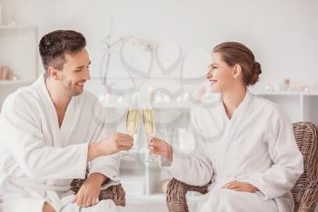 Young couple with glasses of champagne relaxing in spa salon�