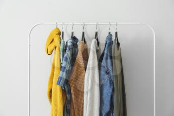 Rack with hanging clothes on light background�