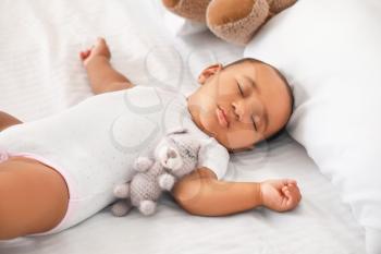 Cute African-American baby sleeping on bed�