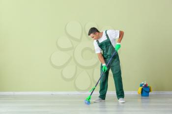 Young man mopping floor in room�