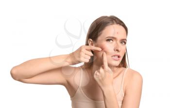 Portrait of young woman with acne problem squishing pimples on white background�