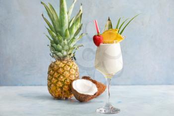 Glass of tasty Pina Colada cocktail and fruits on table�