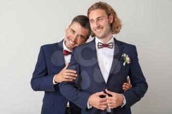 Portrait of happy gay couple on their wedding day against light background�