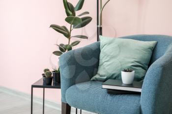 Stylish armchair and table with houseplants in room�